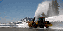 picture of car sized snowblower against 10 foot snow drifts blowing the snow above the drifts